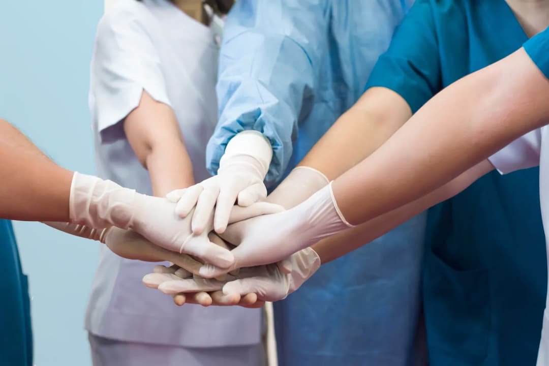 Une équipe de soins rassemble ses mains